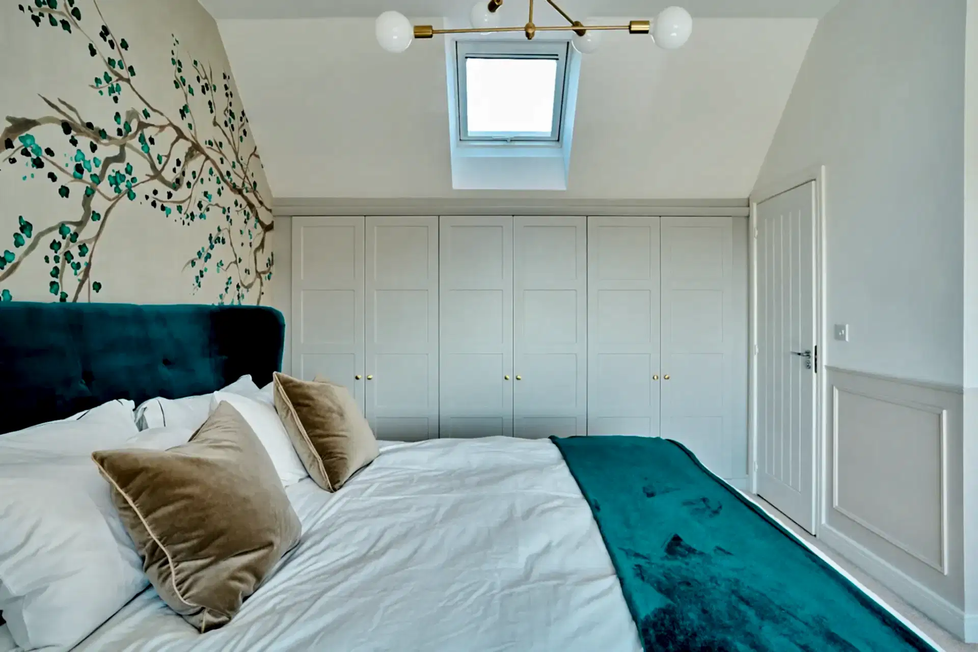 Bright, light loft bedroom with bold teal bed